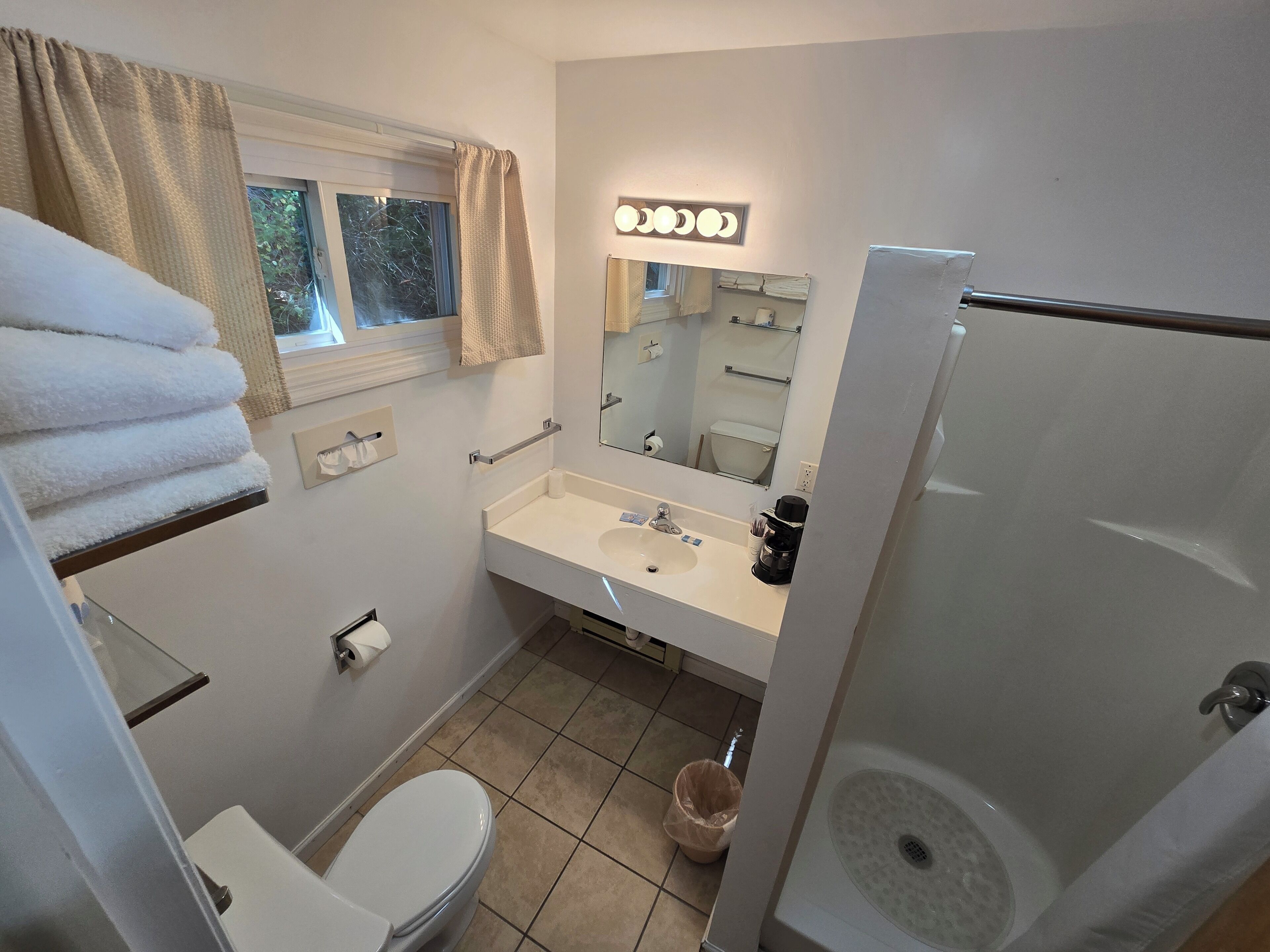 Un baño con inodoro, lavamanos, espejo y ducha.