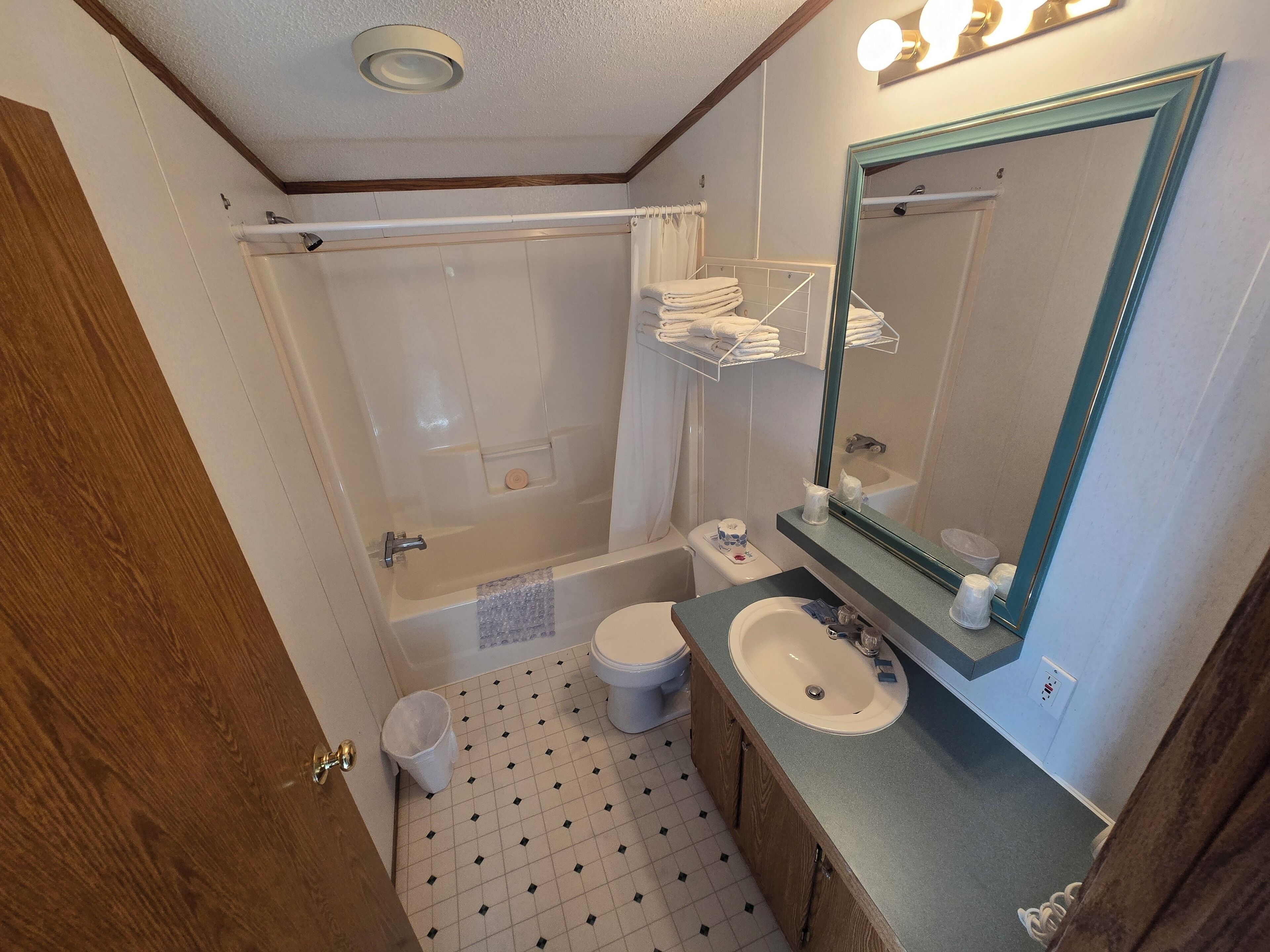 A bathroom with a bathtub, toilet, sink, and a mirror with lights.
