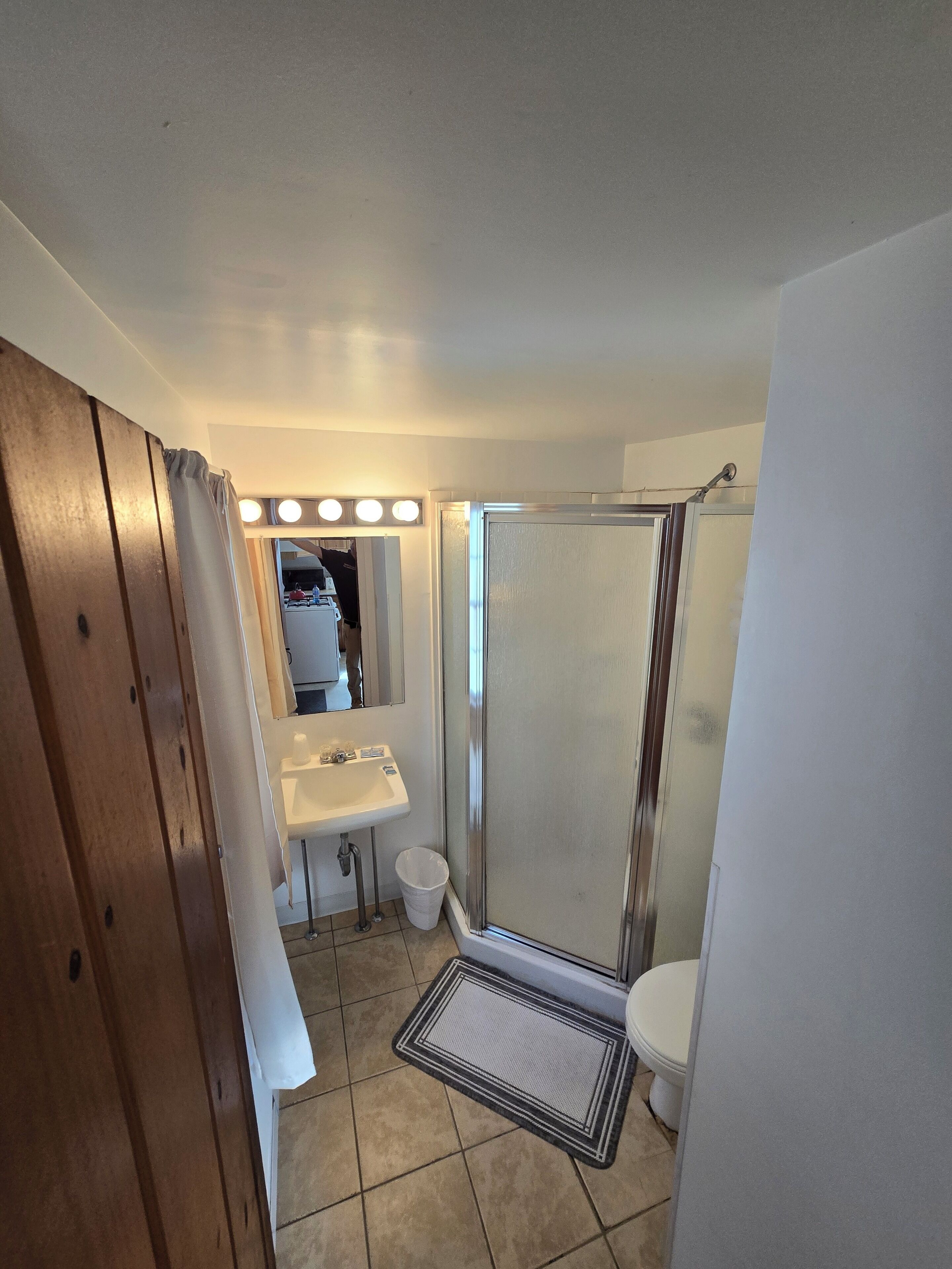 A bathroom with a shower, sink, and mirror.