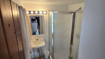 A bathroom with a shower, sink, and mirror.