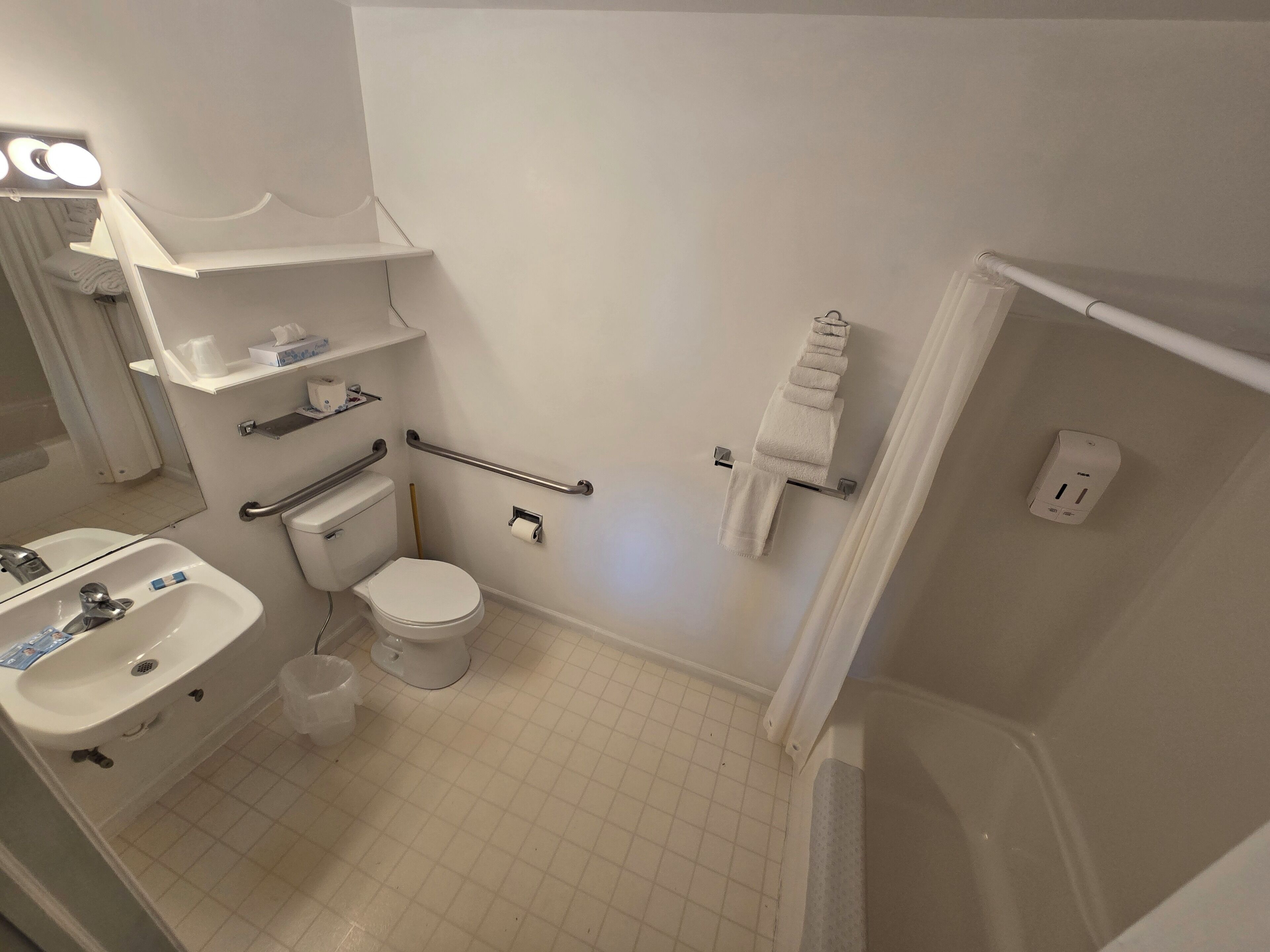 Un baño con inodoro, lavamanos y perchero para toallas.
