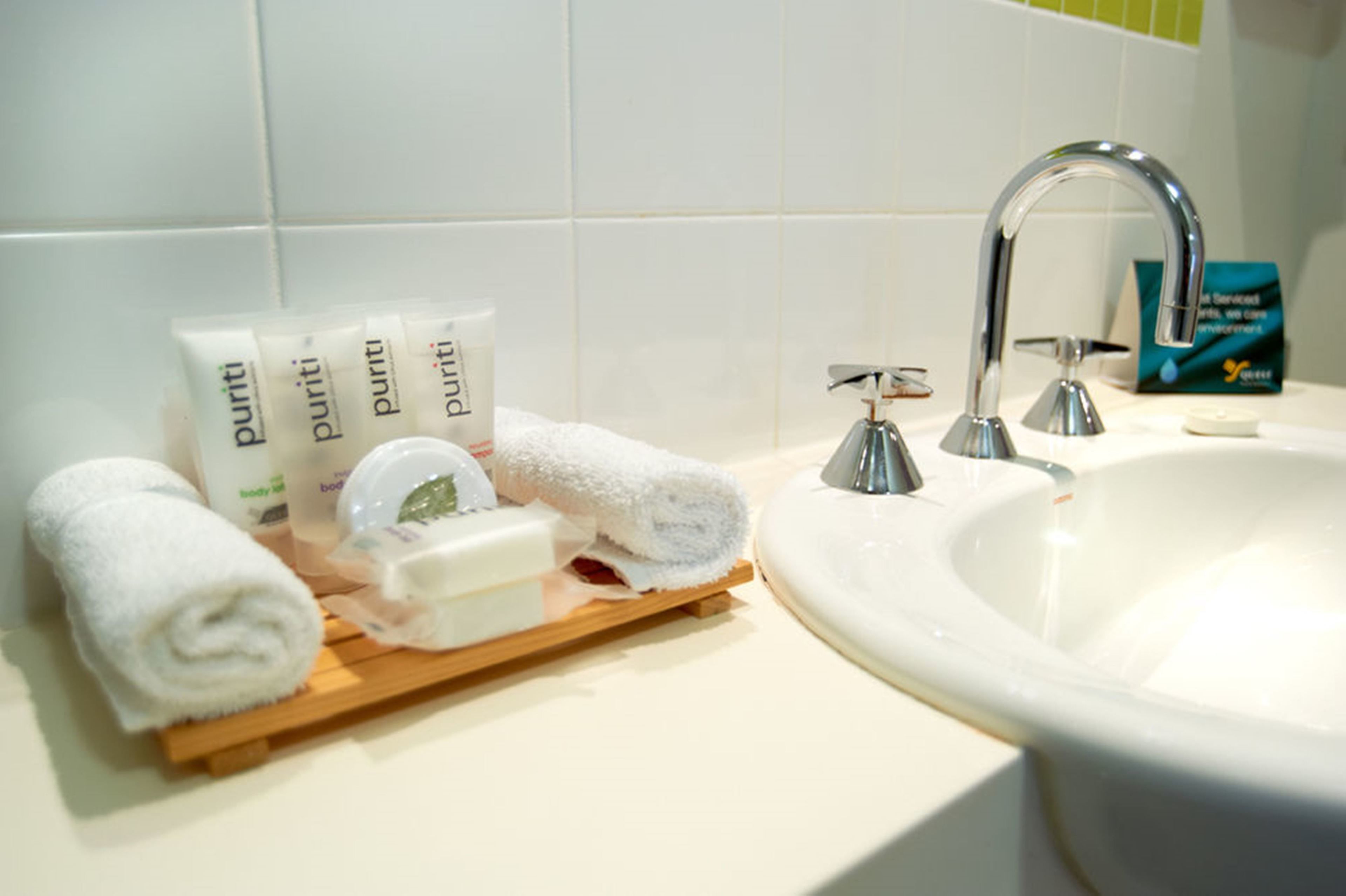 Une salle de bain équipée d’un lavabo, d’articles de toilette et d’un porte-serviettes.