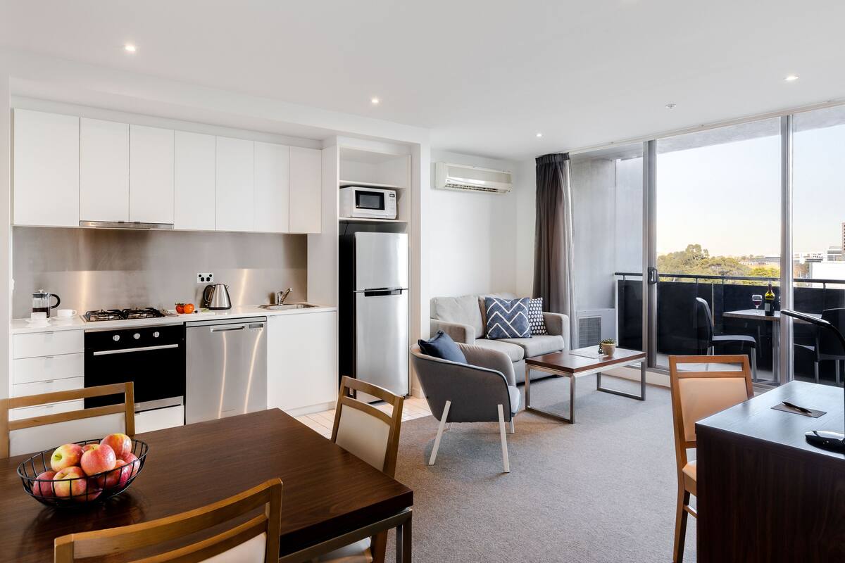 A modern apartment with a kitchen, dining area, and a balcony with a view.