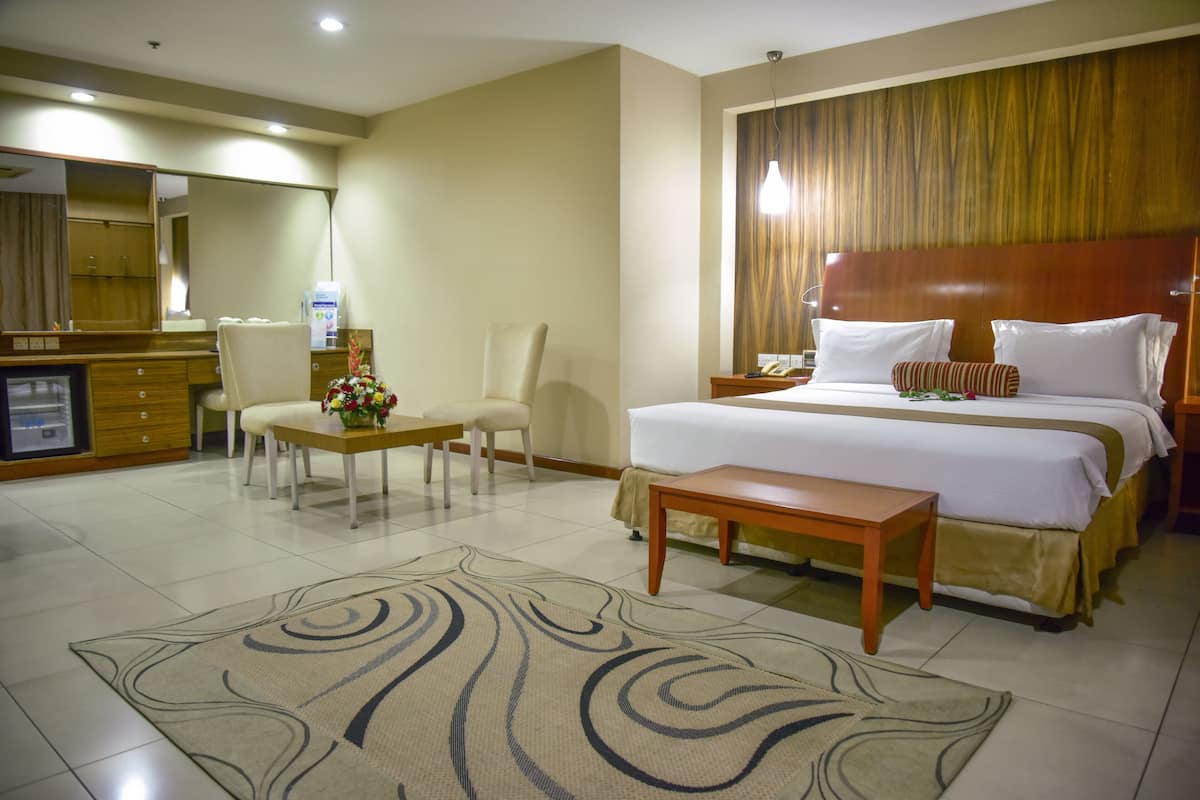 A hotel room with a bed, bedside table, chair, desk, and a large mirror.