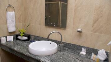 Une salle de bain avec un lavabo blanc, une cabine de douche en verre et un porte-serviettes.
