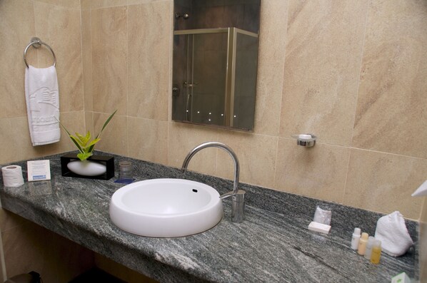 A bathroom with a white sink, a glass shower enclosure, and a towel rack. - Harbour View Suites (Dar es Salaam)