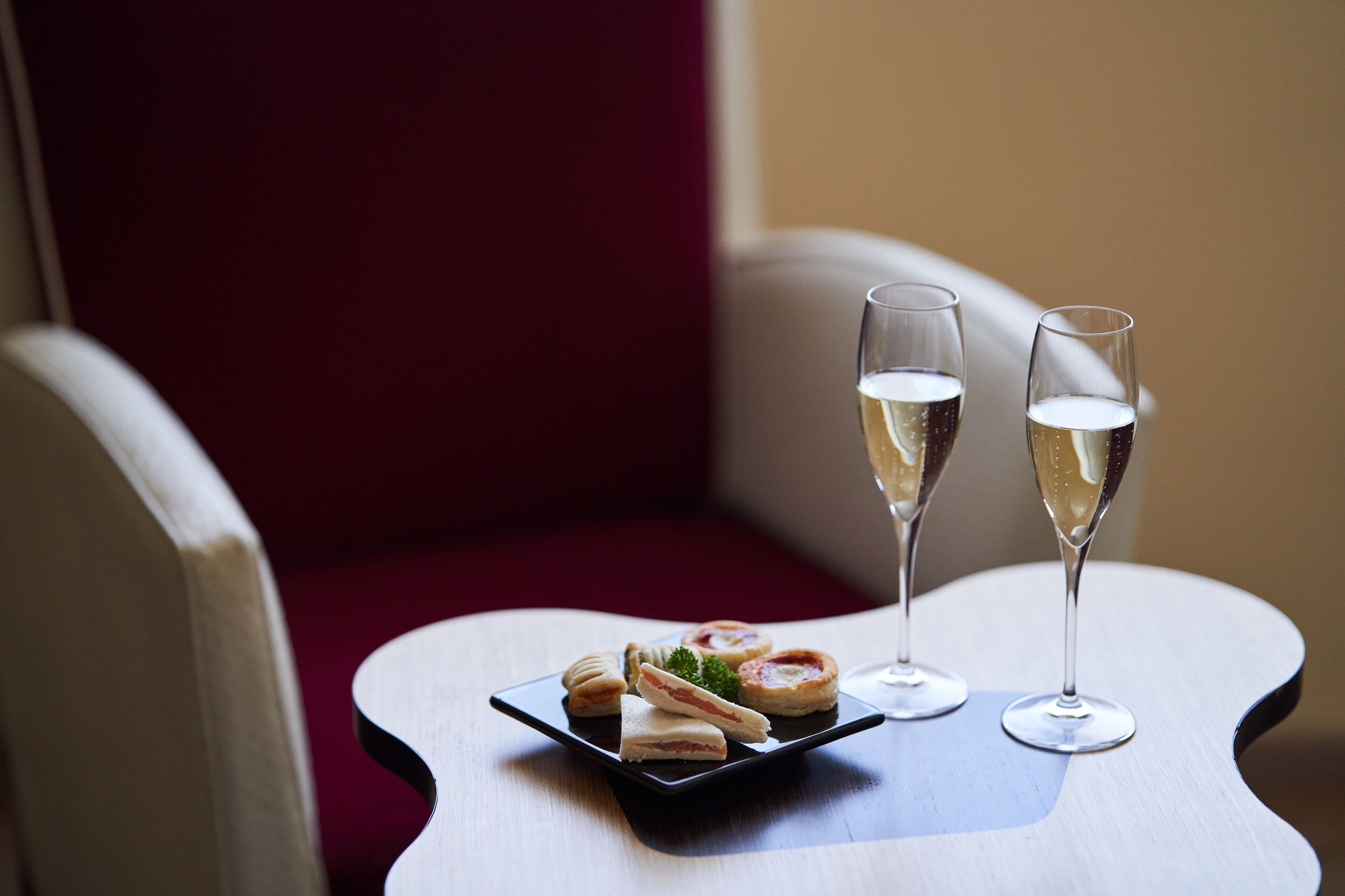 Une table avec deux coupes de champagne et une assiette de pâtisseries.