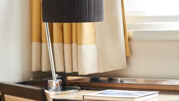 Een bureau met een lamp, een stoel en een raam met gordijnen.