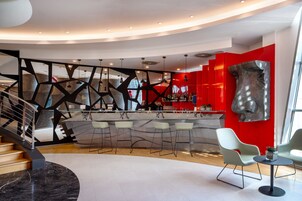A modern bar area with a curved counter, bar stools, and a red accent wall.