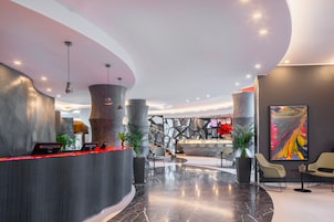 A modern lobby with a curved reception desk, seating area, and a large abstract painting.