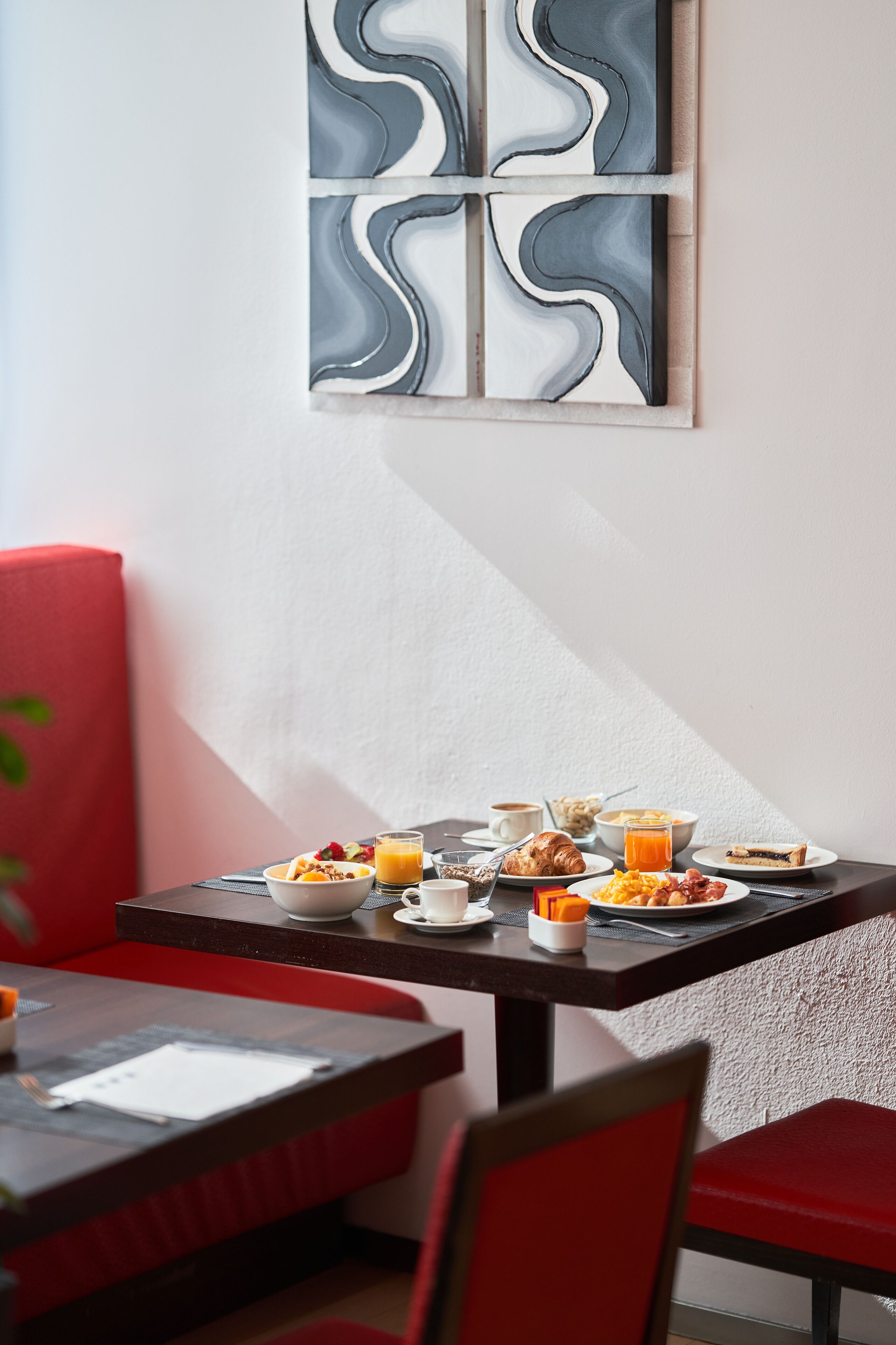 Uma mesa de café da manhã com diversos alimentos, uma xícara de café e um copo de suco de laranja.