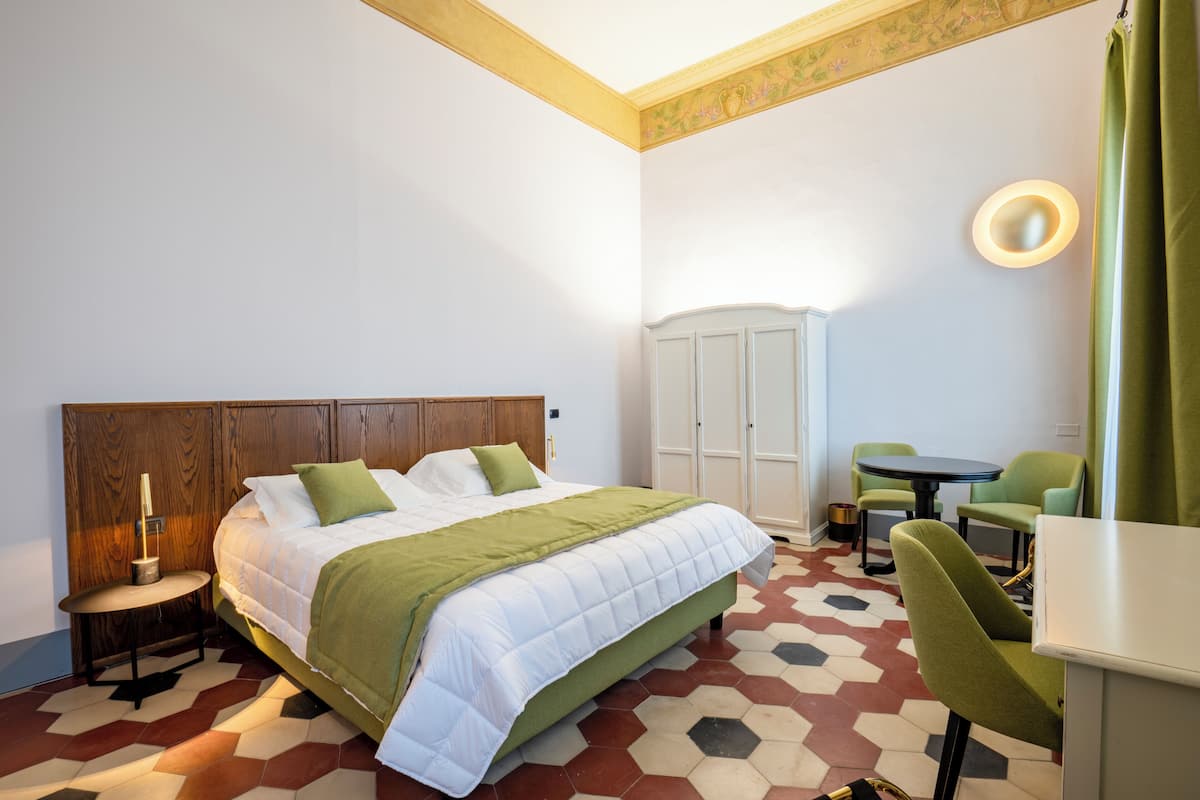 A hotel room with a bed, a desk, a chair, and a wardrobe.