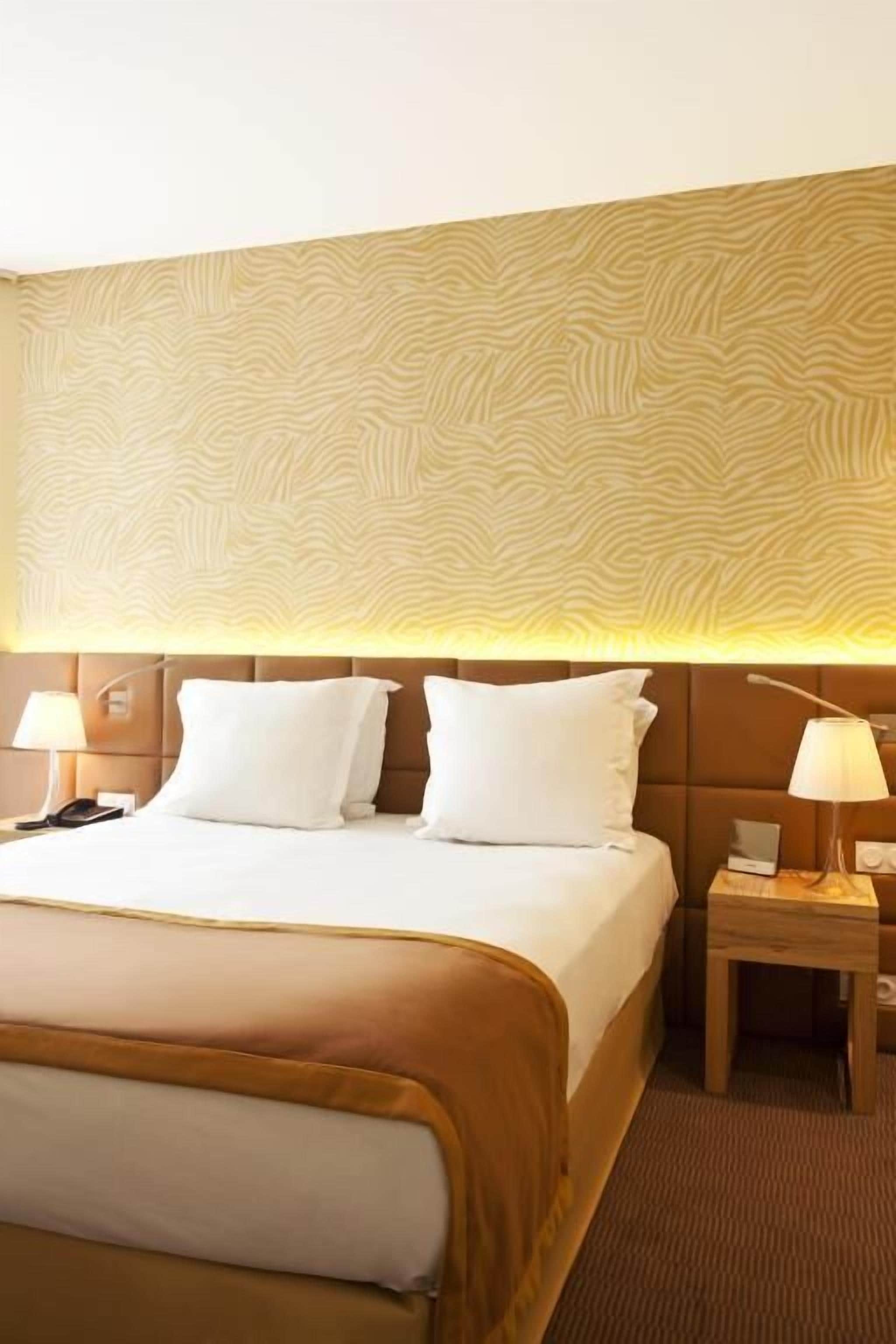 Une chambre d’hôtel avec un grand lit, deux tables de chevet et une tête de lit à motifs.