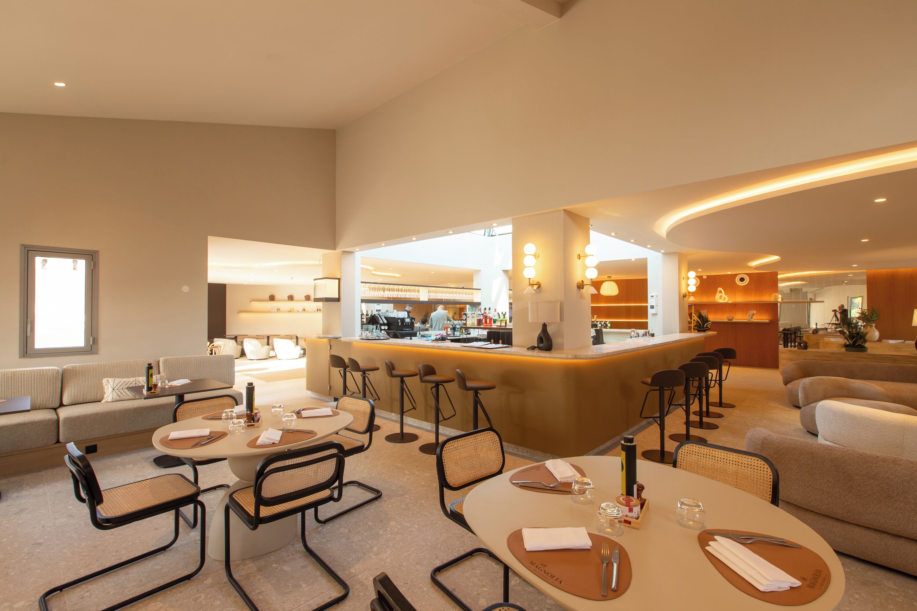 Un lobby moderno de hotel con mesas redondas, zona de bar y asientos.