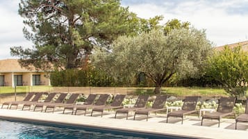 Una piscina al aire libre, sillones reclinables de piscina