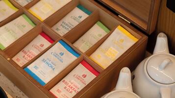 Une boîte en bois étiquetée « La Route des Comptoirs » contenant des sachets de thé et des théières blanches.