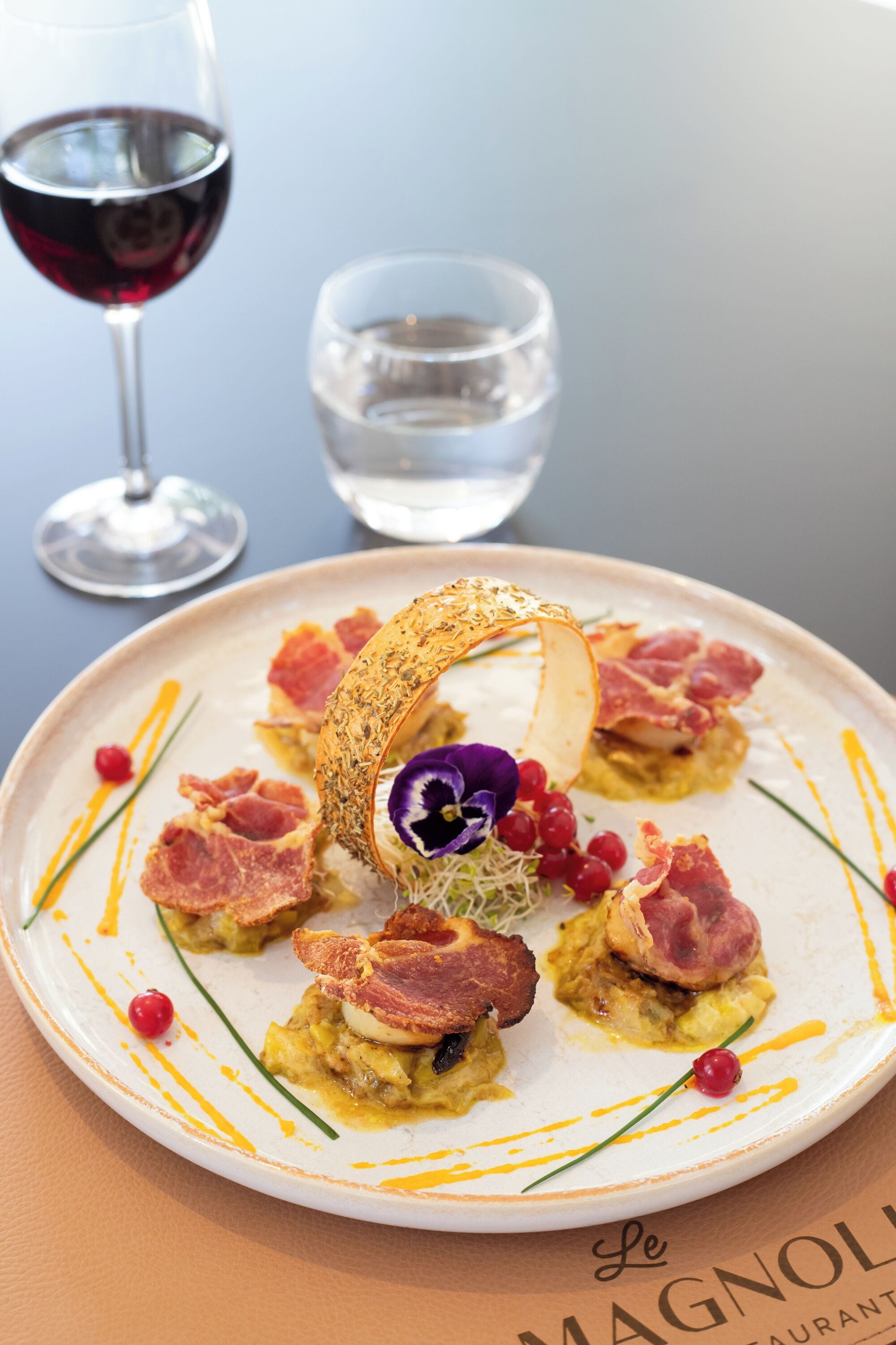 Une assiette de nourriture agrémentée de diverses garnitures et un verre de vin rouge.