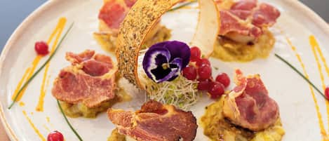 A plate of food with various garnishes and a glass of red wine.