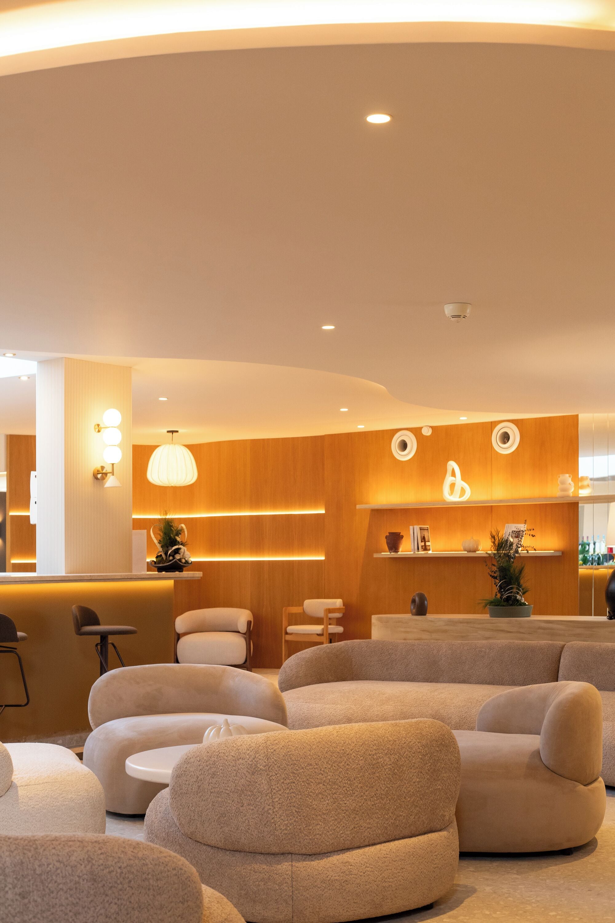 A modern interior with a reception desk, plush seating, wooden paneling, and ambient lighting.