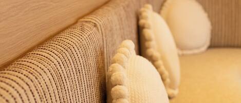 A sofa with a textured fabric and a round, white cushion.
