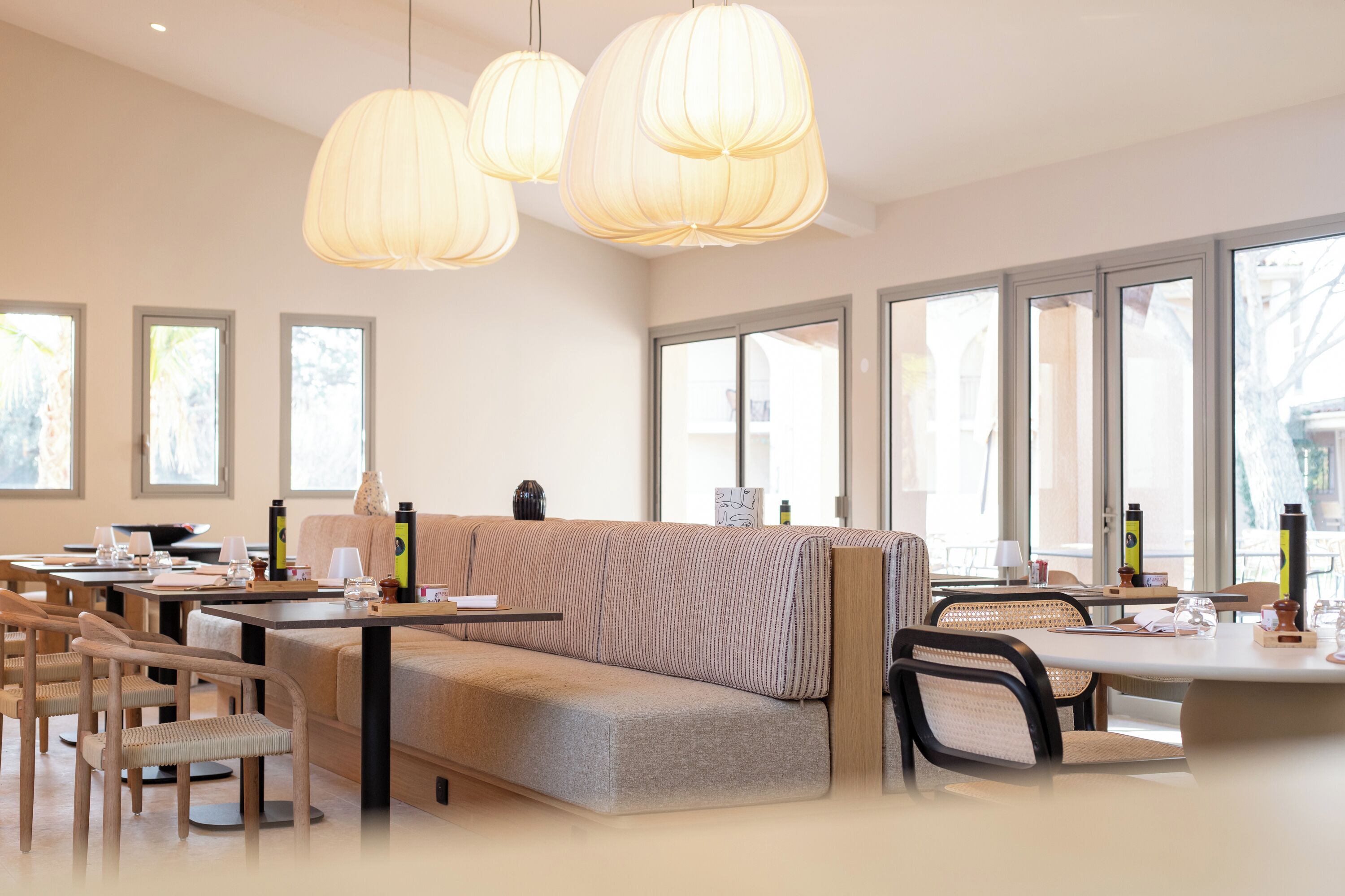 A modern dining area with a sofa, chairs, and pendant lights.