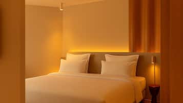 Una habitación de hotel con una cama grande, una mesita de noche y una lámpara fijada a la pared.
