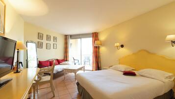 Quarto de hotel com cama, escrivaninha, cadeira, televisão e varanda com vista.