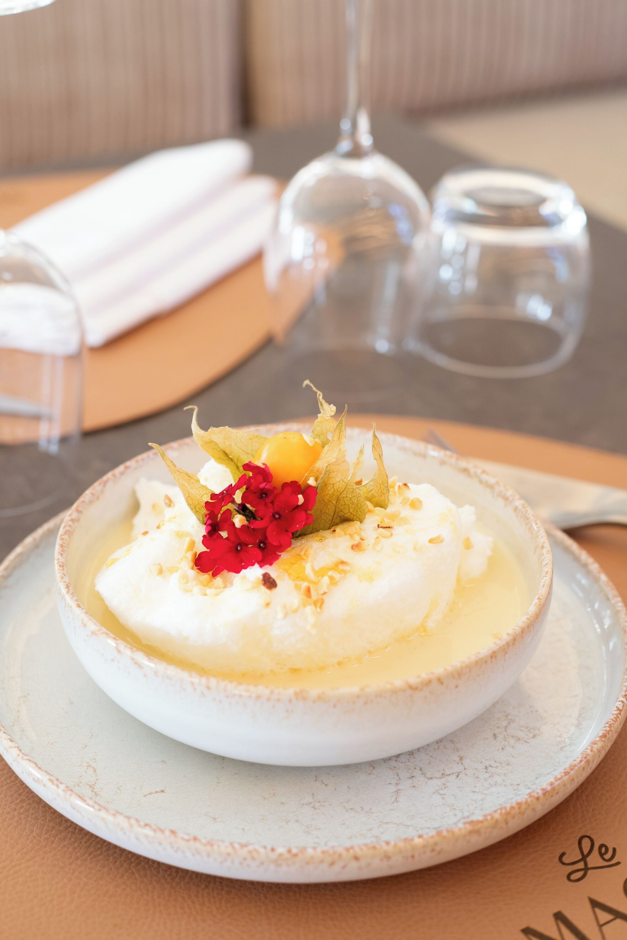 A dessert on a plate with a napkin and glasses in the background.