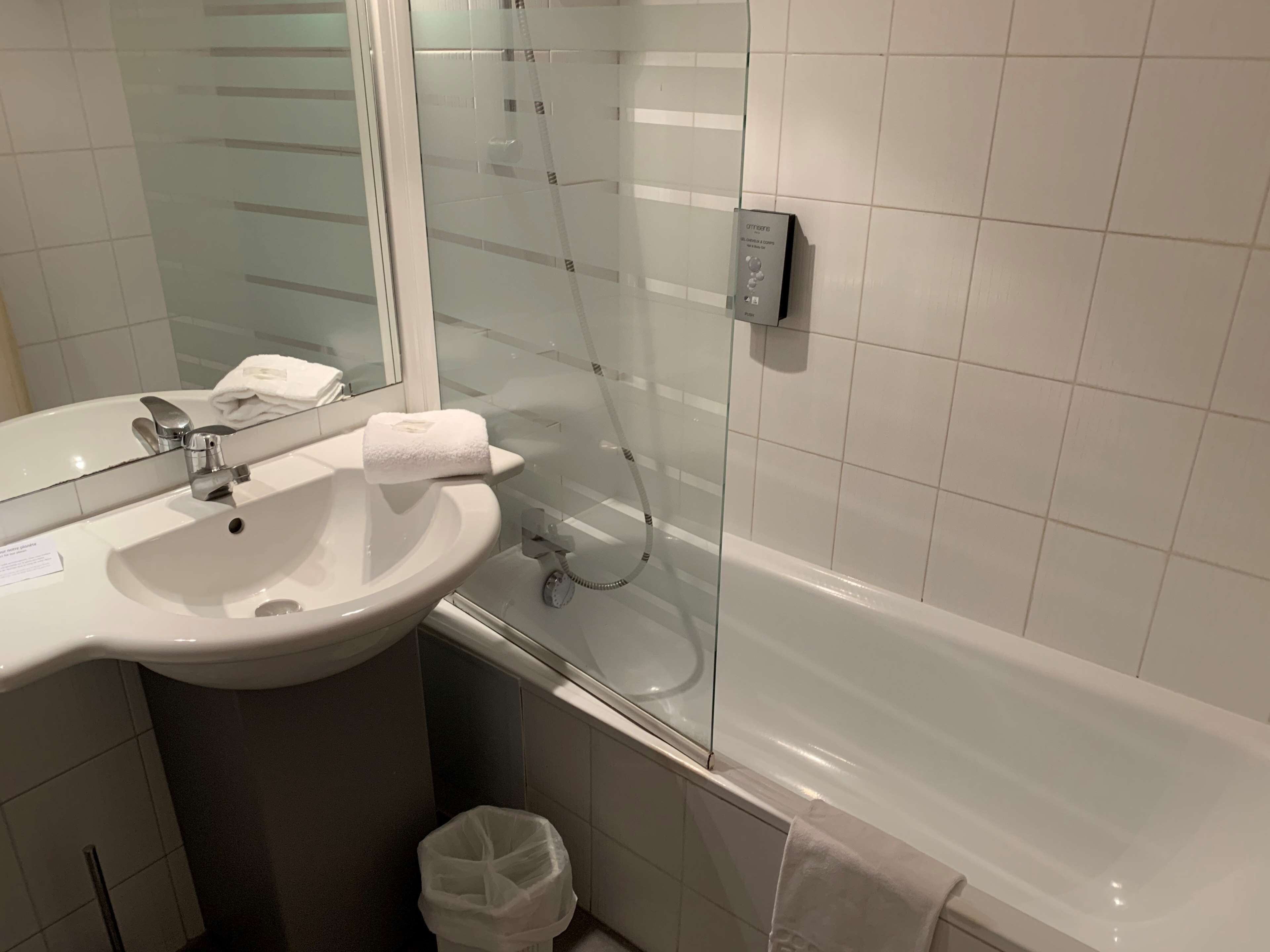A bathroom with a white sink, a mirror, a glass shower enclosure, and a white bathtub.