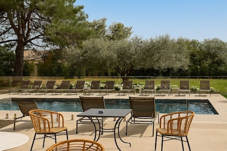 Una piscina al aire libre, sillones reclinables de piscina