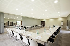 Meetings take place in this spacious room with a long table, whiteboard, and projector screen.