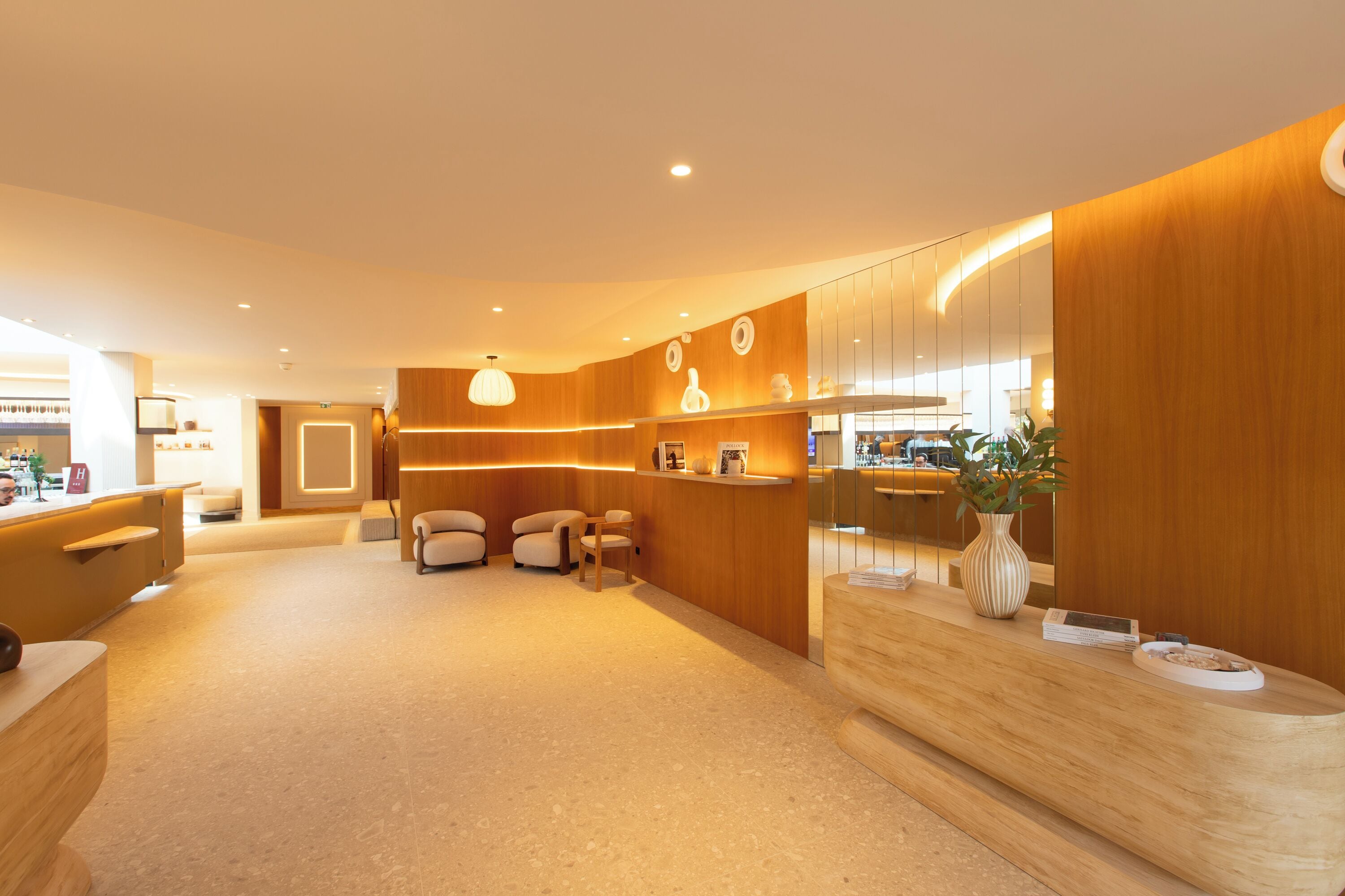 A modern reception area with a wooden reception desk, seating area, and a large mirror.