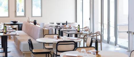 Un comedor moderno con mesas redondas, sillas de metal negro e iluminación colgante.