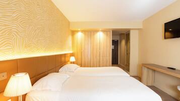 Une chambre d’hôtel avec un grand lit, une lampe de chevet, un téléviseur fixé au mur et un mur décoré de panneaux en bois.
