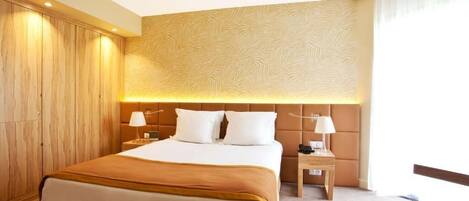A hotel room with a large bed, two bedside tables, a headboard with a textured pattern, and a wooden wardrobe.