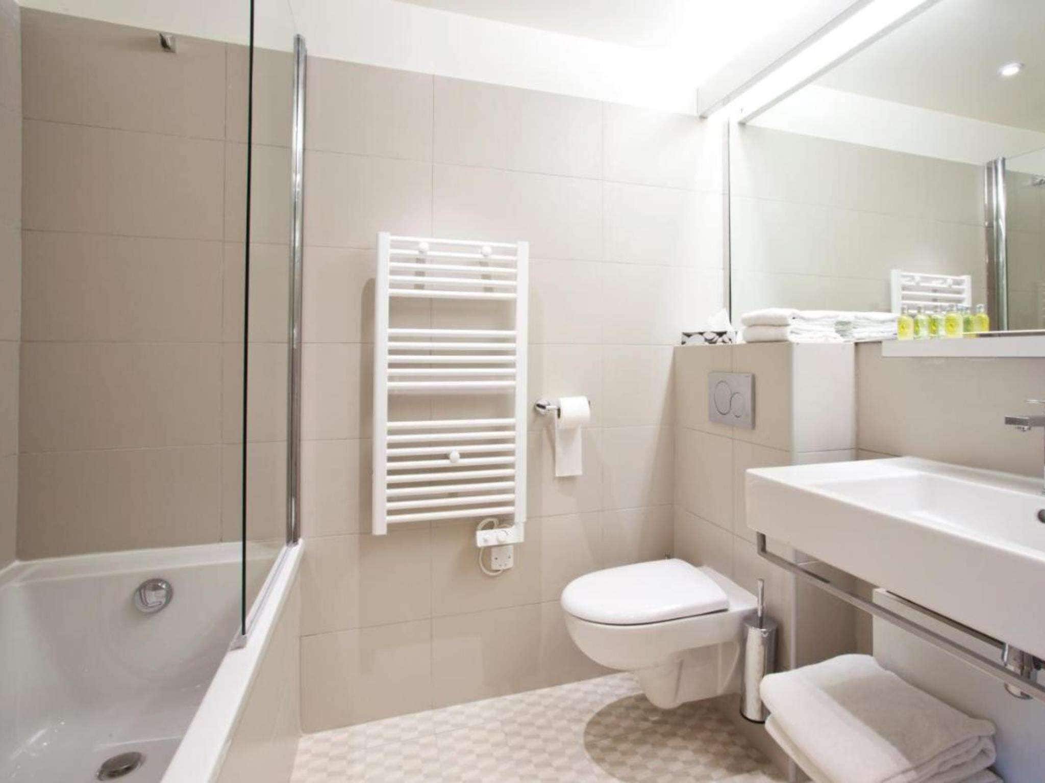 A modern bathroom with a glass-enclosed shower, a toilet, and a sink with a mirror.