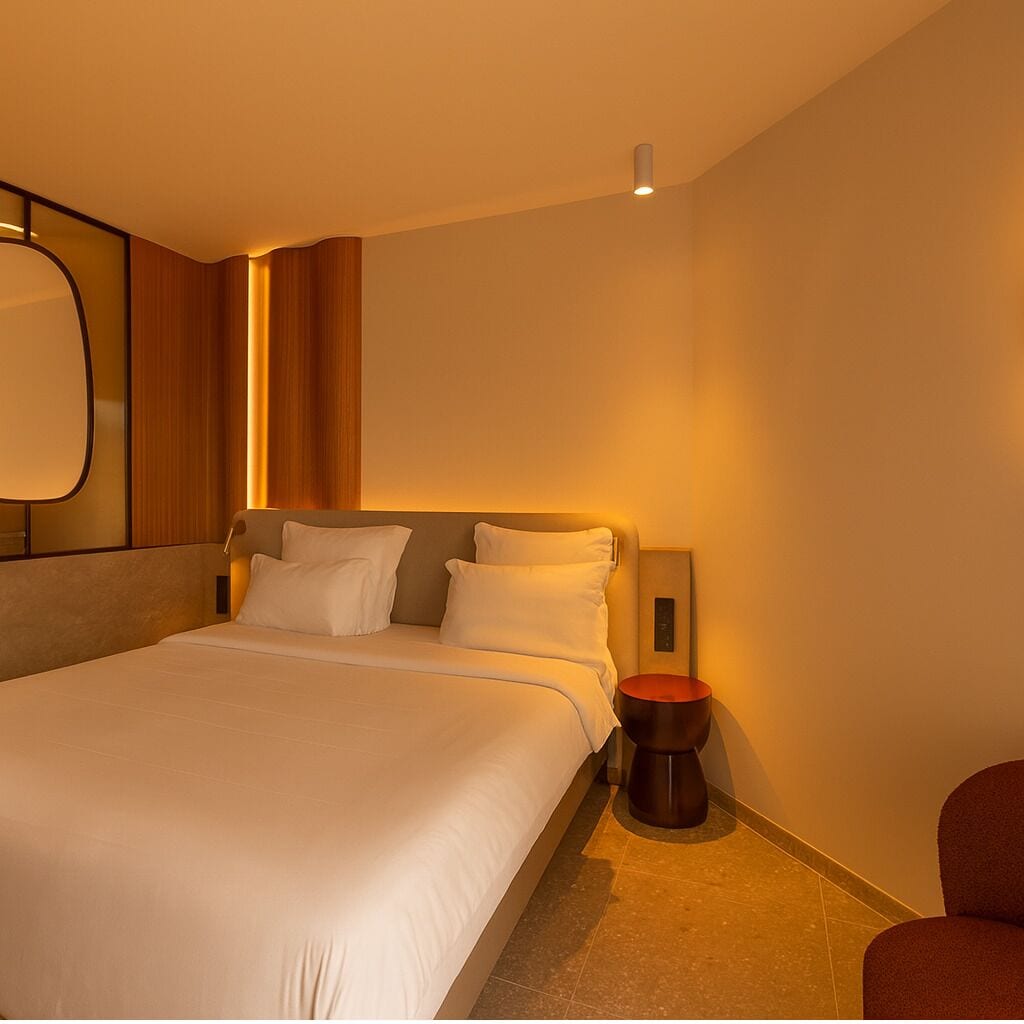 Una habitación de hotel moderna con una cama grande, una mesita de noche y una silla.