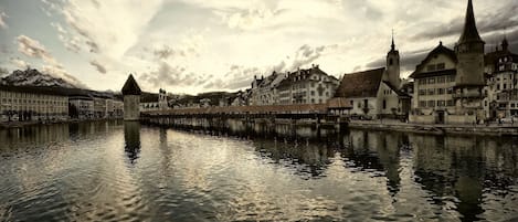 Un pueblo histórico con un río, destacando arquitectura tradicional, una torre imponente y un puente.