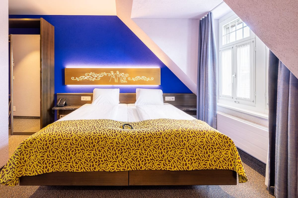 Ett hotellrum med en säng, ett skrivbord och ett fönster.
