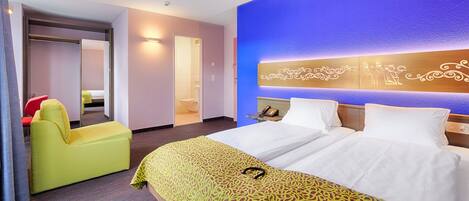 A hotel room with a bed, a chair, a mirror, and a bathroom visible through an open door.