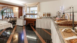 Uma área de buffet com mesas, um canto para café e diversas opções de comida.