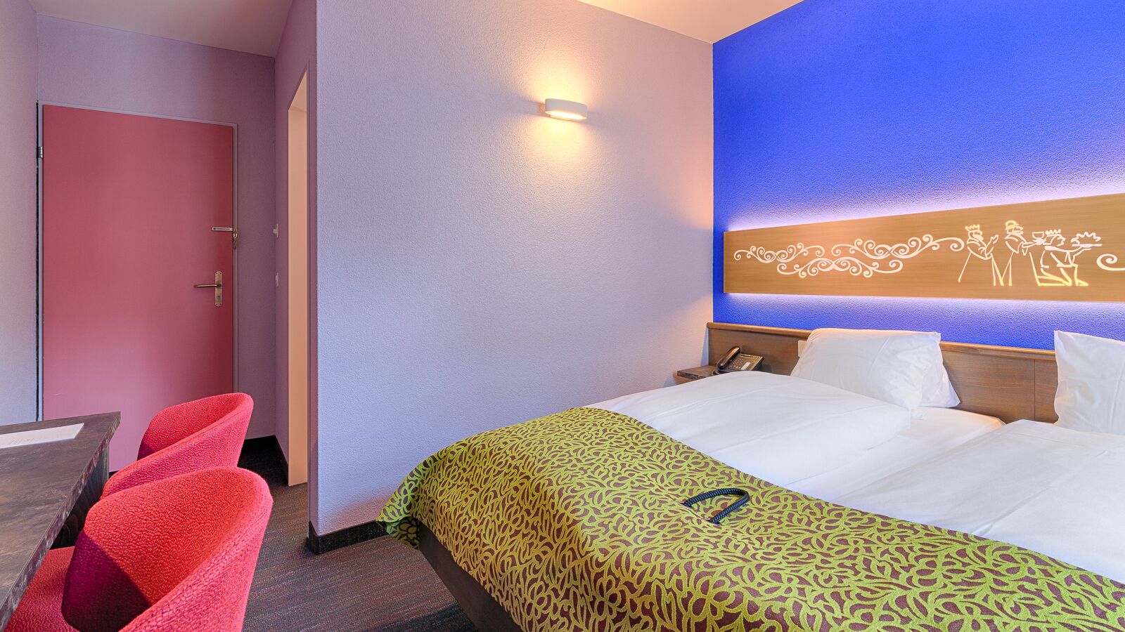 Una habitación de hotel con una cama, un escritorio y dos sillas.