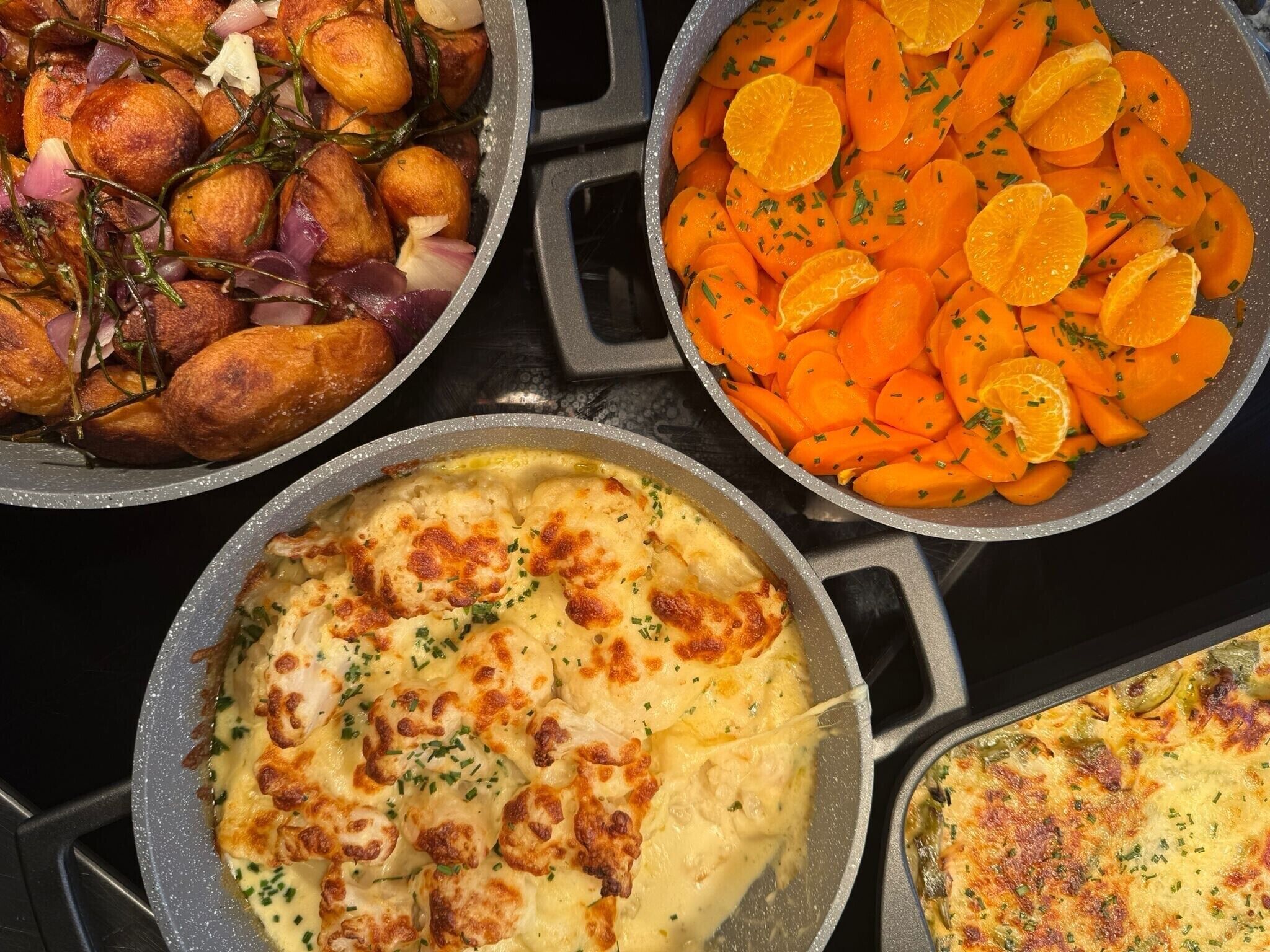 Tres platos en una sartén: patatas asadas, zanahorias en rodajas y un pastel horneado.