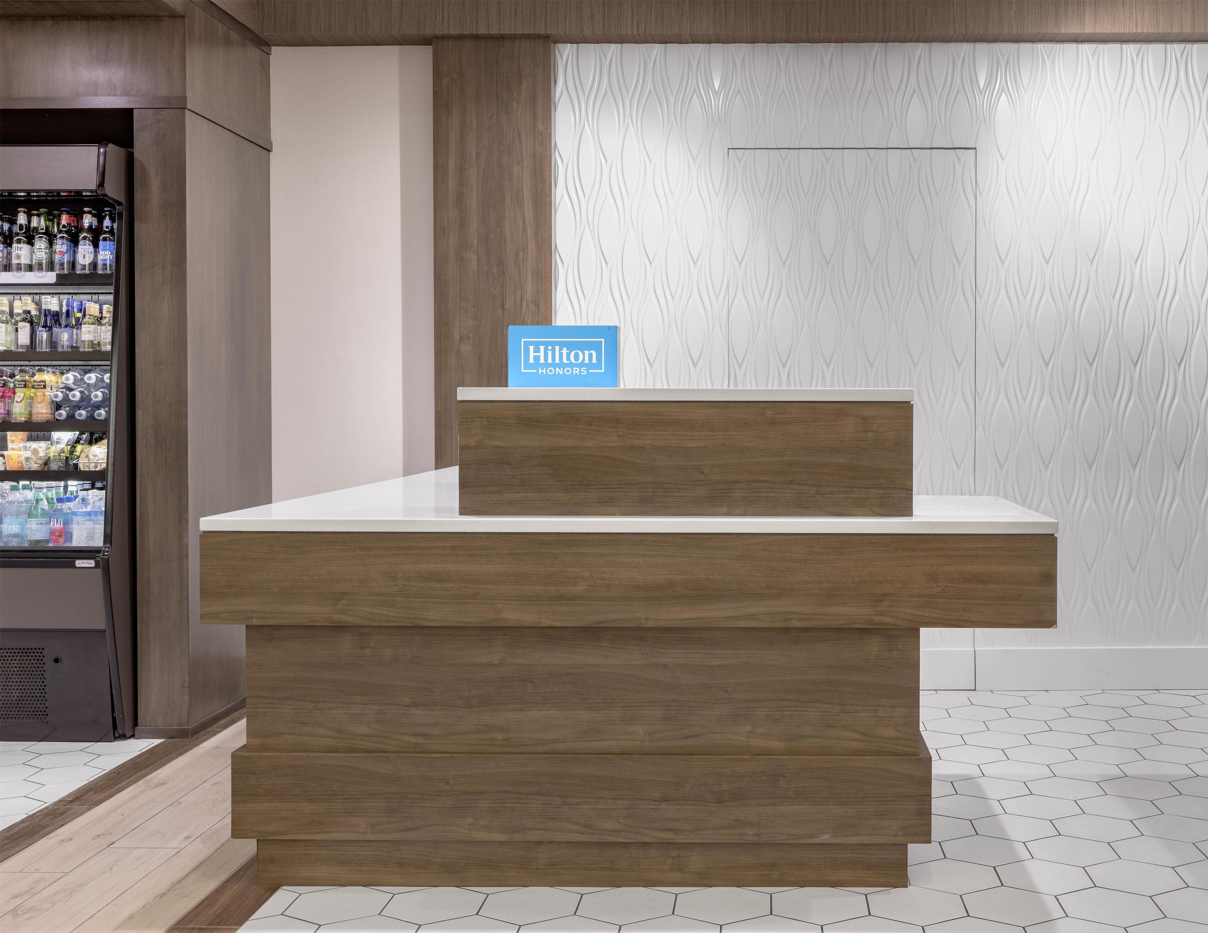 Een receptiebalie met een houten afwerking en een bordje met Hilton Honors.