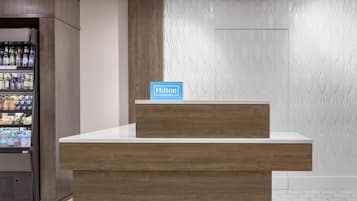 Een receptiebalie met een houten afwerking en een bordje met Hilton Honors.