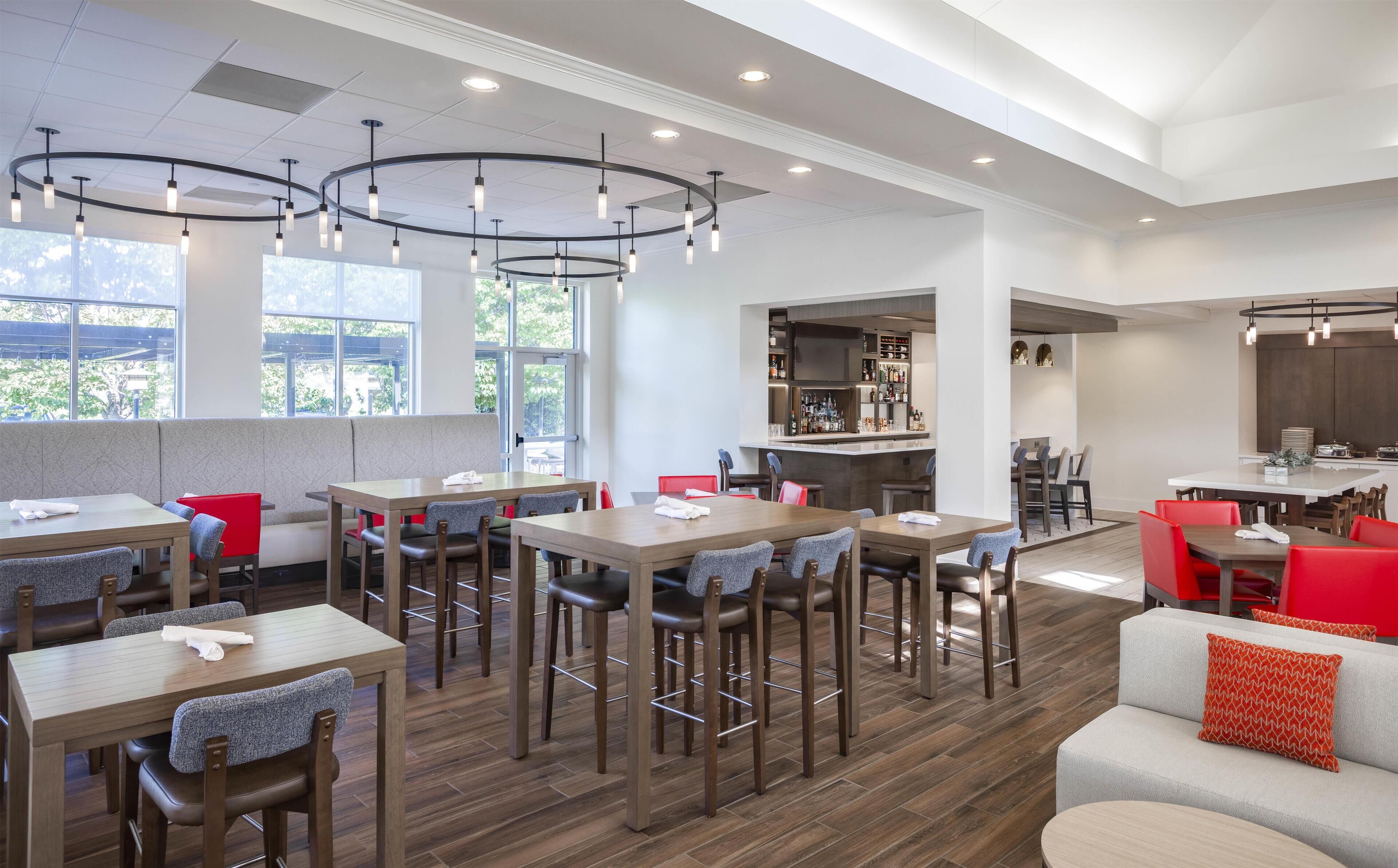 A modern restaurant with multiple dining areas, a bar, and a seating area with a view.