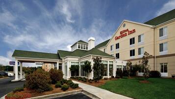 A Hilton Garden Inn with a covered parking area and a well-maintained lawn.