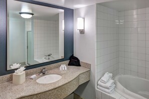 Un baño con lavamanos, espejo, toallero y bañera.
