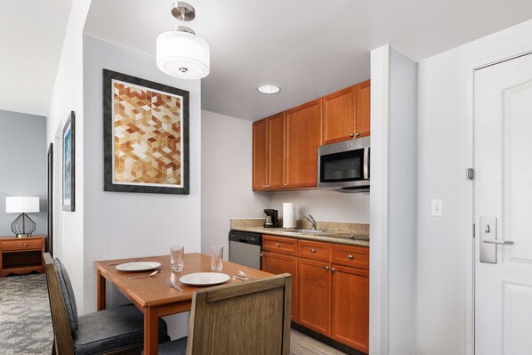 A modern kitchen with wooden cabinets, a microwave, and a dining area with a table and chairs.