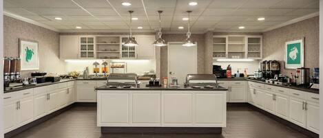 Una cocina amplia con armarios blancos, una isla central e iluminación colgante.